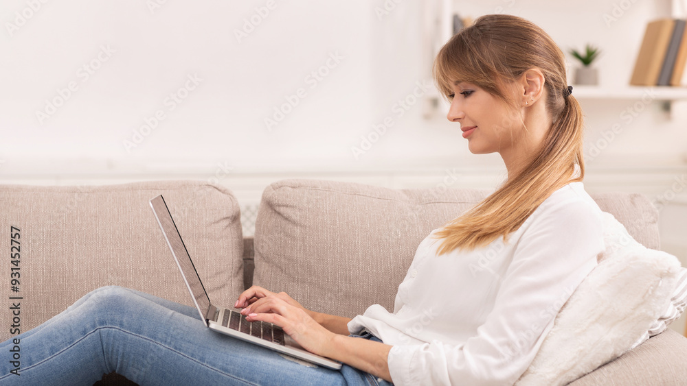Woman Working On Laptop Computer Writing Article For Blog Sitting On Sofa Indoor. Successful Freelancer Working At Home Woman Working On Laptop Computer Writing Article For Blog Sitting On Sofa Indoor. Successful Freelancer Working At Home