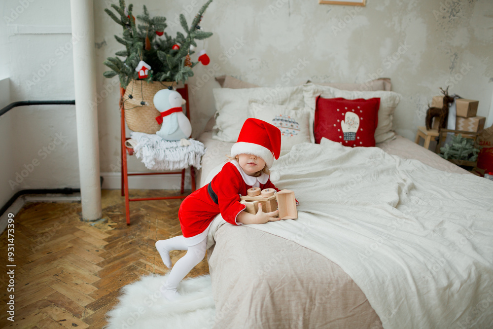 Fototapeta premium A little girl santa claus with gifts in the bedroom