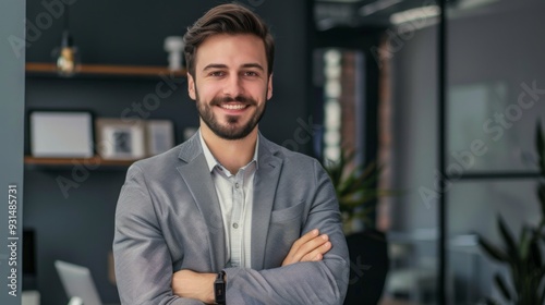 Smiling handsome businessman with crossed arms in modern office, young man exuding confidence, business success concept.