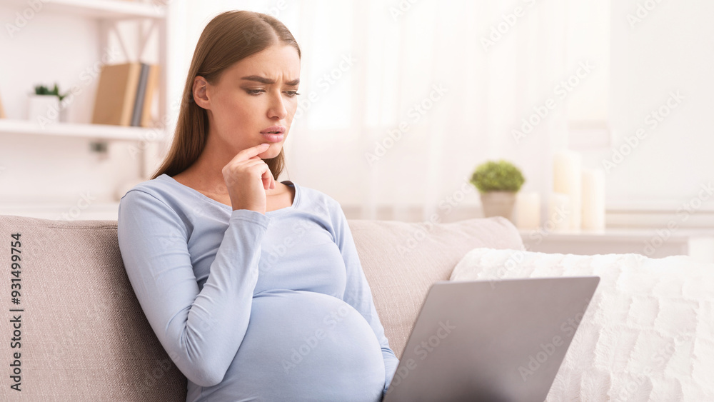 Pensive Pregnant Woman Using Laptop Computer Browsing Internet Sitting On Couch At Home. Selective Focus Pensive Pregnant Woman Using Laptop Computer Browsing Internet Sitting On Couch At Home. Selective Focus