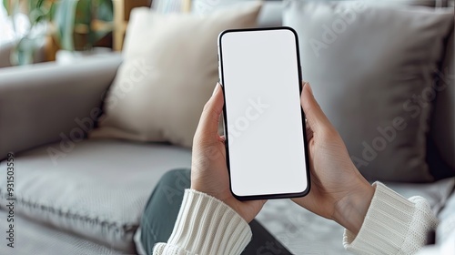 Woman holding smartphone with blank screen on a sofa