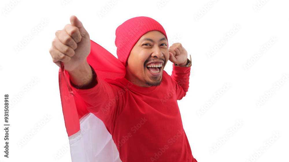 Happy Indonesian man wearing a red long sleeve T-Shirt and a red beanie hat holds Indonesia's flag to celebrate Indonesia Independence Day on August 17. Isolated on a white background.