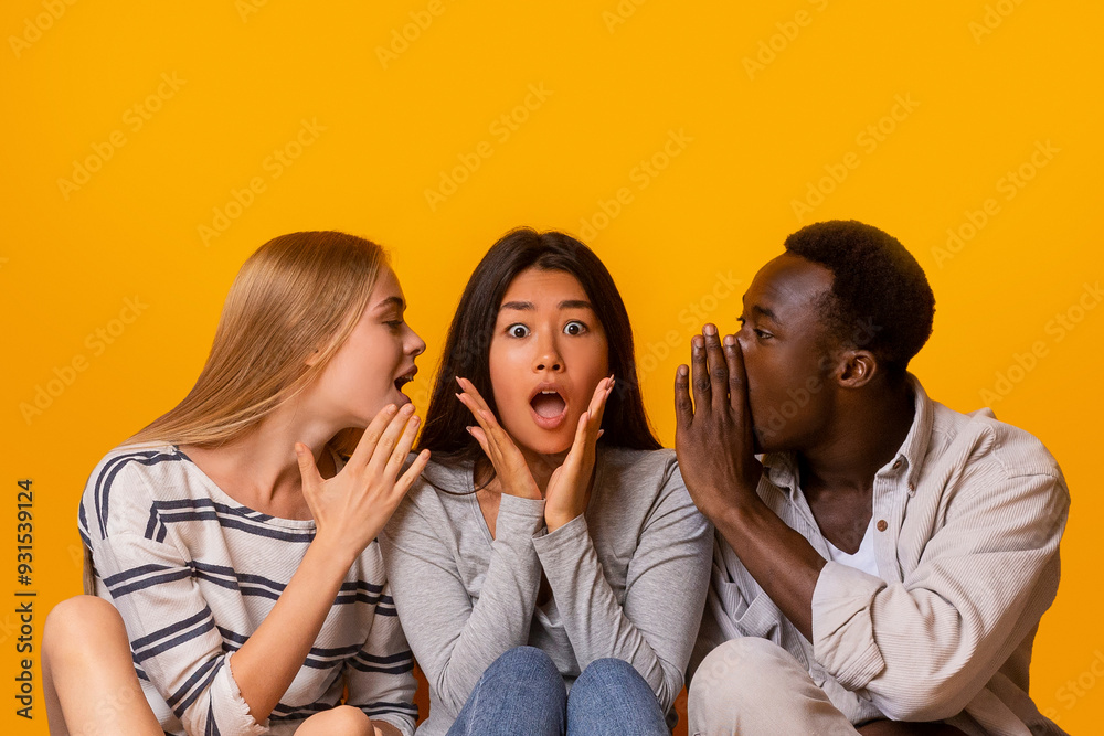 International friends sitting in row on floor, gossiping over yellow studio background, student lifestyle International friends sitting in row on floor, gossiping over yellow studio background, student lifestyle