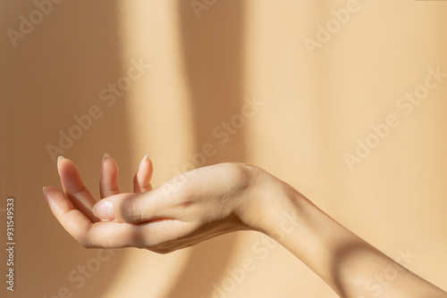 Beautiful female hand in close-up on brown background in rays of sunlight. The concept of hands care. photo