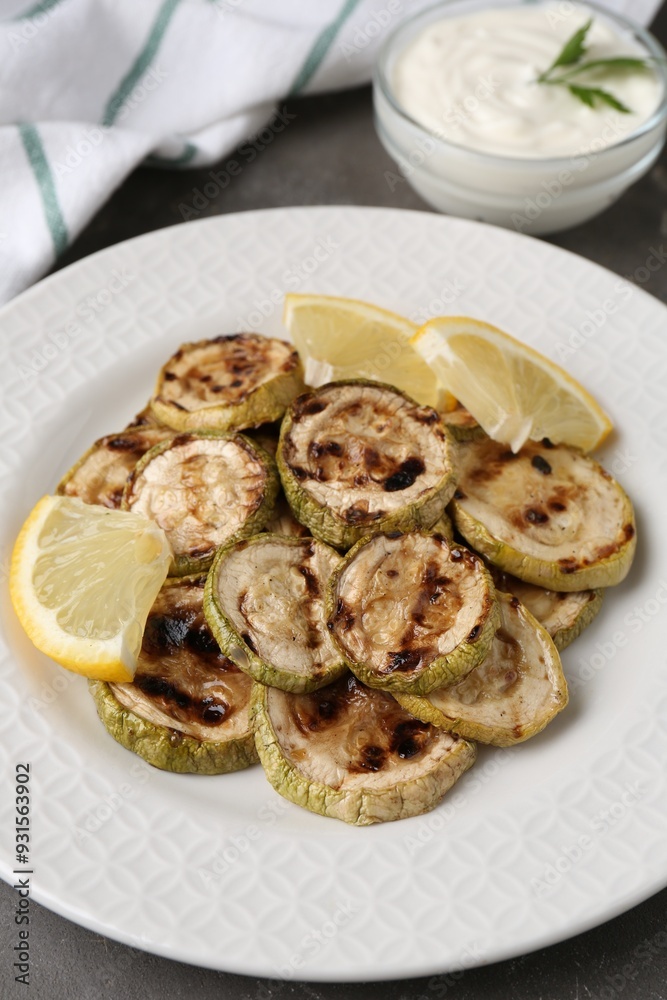 Tasty grilled courgette slices with lemon on grey table Tasty grilled courgette slices with lemon on grey table
