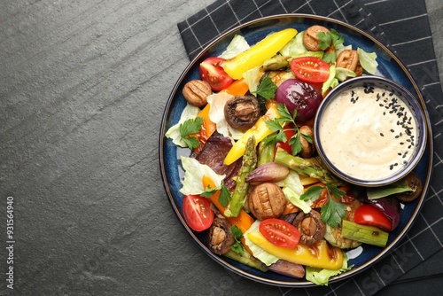 Delicious salad with grilled vegetables and sauce on dark gray textured table, top view. Space for text