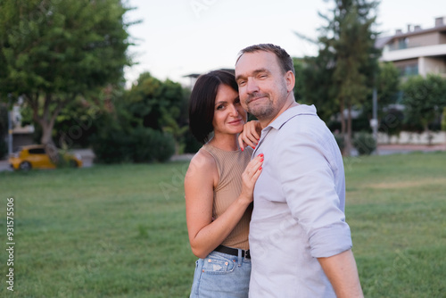 A happy smiling couple walking, hugging and kissing in park on late summer sunset photo