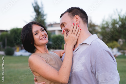 A happy smiling couple walking, hugging and kissing in park on late summer sunset photo