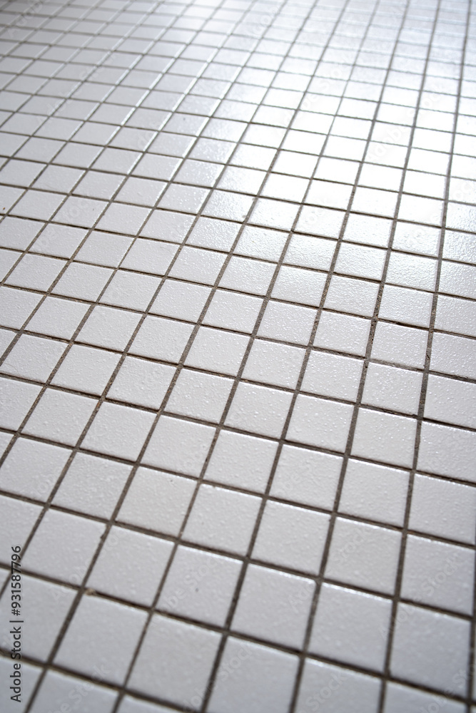 Small, white, ceramic tile flooring inside apartment bathroom, close up shot, no people