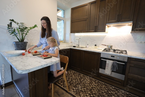 Mother and a small daughter cooking food at home in the kitchen