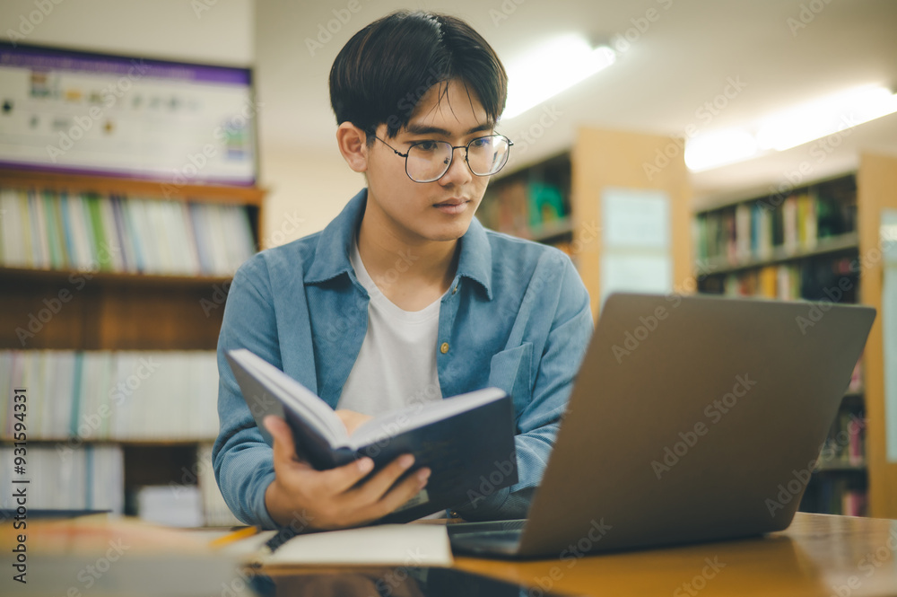 Male college students are working on laptops and searching for books to study, make reports, find useful information in college room. Concept of reading, learning and intelligence. Male college students are working on laptops and searching for books to study, make reports, find useful information in college room. Concept of reading, learning and intelligence.