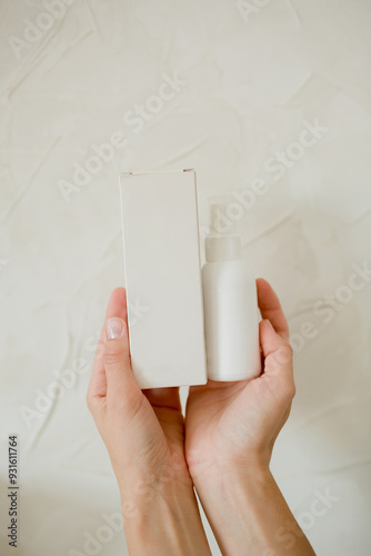 hands holding white bottle and box for cosmetics