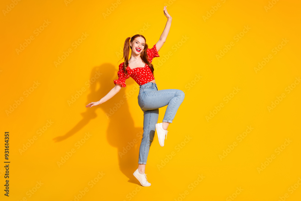 Photo portrait of young red hair funky positive girl wearing blouse and jeans dancing enjoy music isolated on yellow color background Photo portrait of young red hair funky positive girl wearing blouse and jeans dancing enjoy music isolated on yellow color background