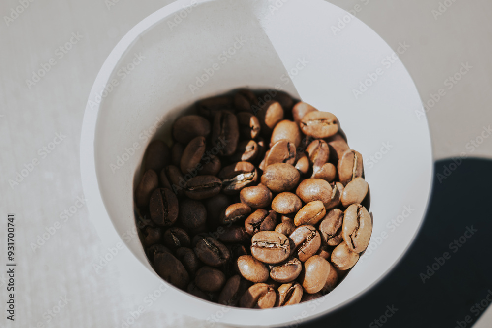White cup with roasted coffee beans top view. The concept of quality coffee and roasters White cup with roasted coffee beans top view. The concept of quality coffee and roasters