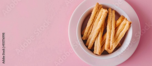 Breadsticks toppled a white cup against a pink background with copyspace Horizontal layout