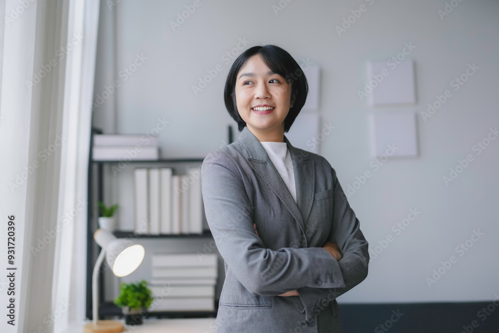 Young asian businesswoman smiling while standing with her arms crossed in a modern office Young asian businesswoman smiling while standing with her arms crossed in a modern office