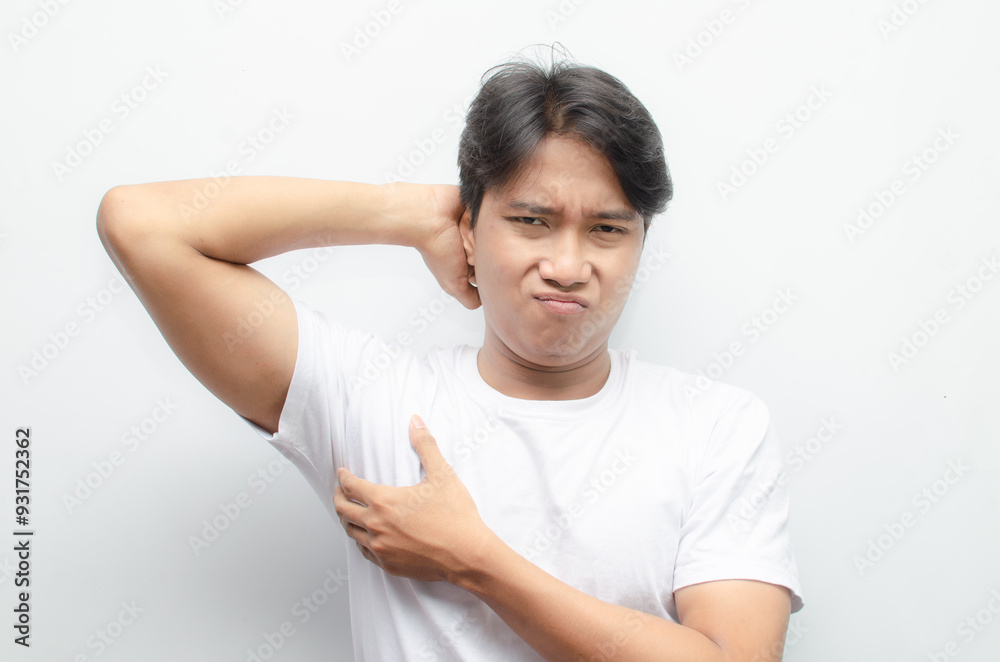 young asian man in white tshirt feeling embarrased because of his body odor. man smelling bad odor on his armpit.
