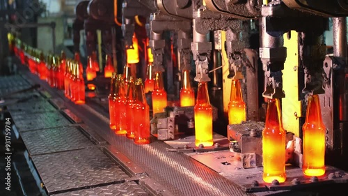 Glass factory, production of glass containers. Molten glass is blown into molds. Robotics in industry. Modern technologies, robotic machines produce products. Technological work at the plant.