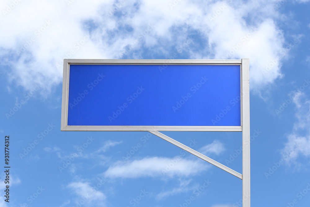 Empty blue sign with a background of a blue sky and white clouds.