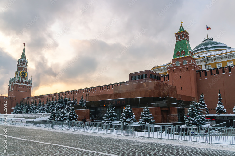 Fototapeta premium The Kremlin Wall in winter in Moscow. The mausoleum near the Kremlin on Red Square. Snow-covered fir trees in front of the Moscow Kremlin. The defensive wall surrounding the Kremlin.