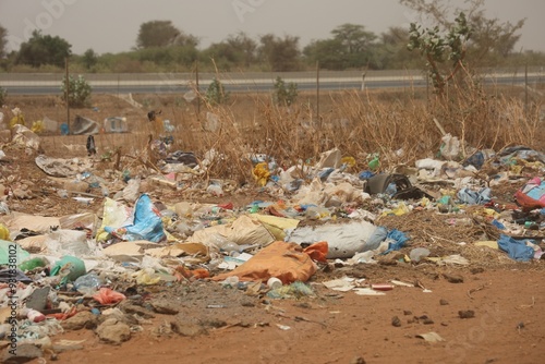 Vue rapprochée d'une décharge sauvage au Sénégal composée de déchets en plastique et d'emballages en carton et située près d'une route. Symbole de la pollution et de la dégradation de l'environnement. photo