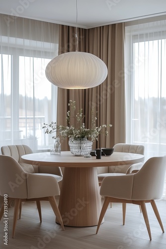 A modern dining room with a round table, elegant chairs, and a large pendant light, with soft lighting and a minimalist decor scheme.