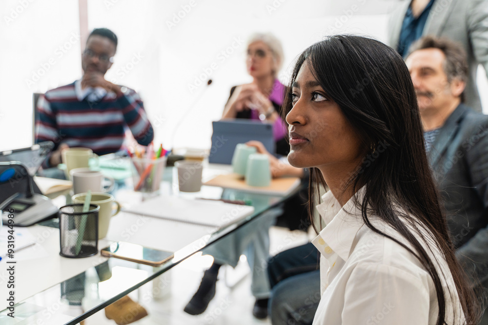 Diverse business team in meeting, focus on attentive female professional Diverse business team in meeting, focus on attentive female professional