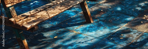 Sunlight and shadows cast on vintage wooden playground equipment atop a blue rubber tile surface in a garden area of a park. photo