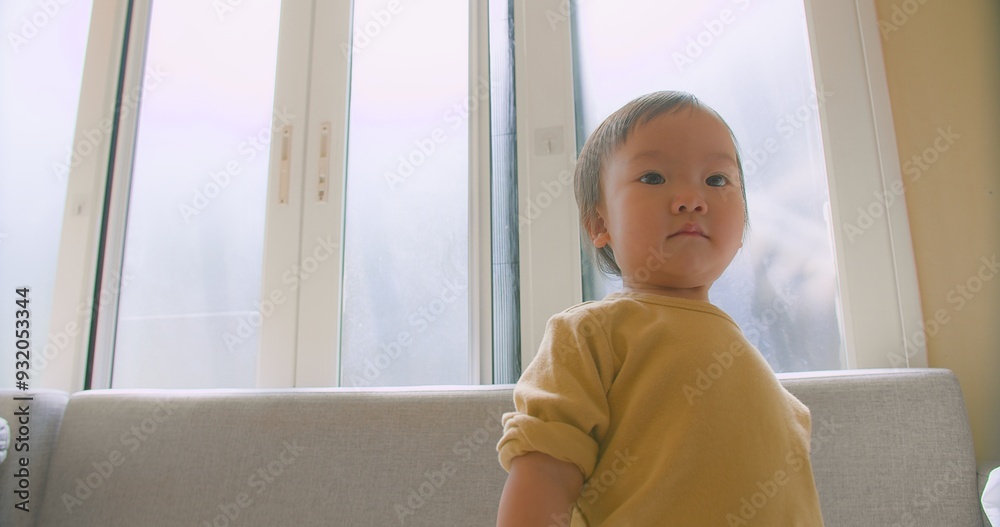 Portrait happy little cute Asian toddler child girl looking smiling and dancing jump having fun on sofa in living room at home Portrait happy little cute Asian toddler child girl looking smiling and dancing jump having fun on sofa in living room at home