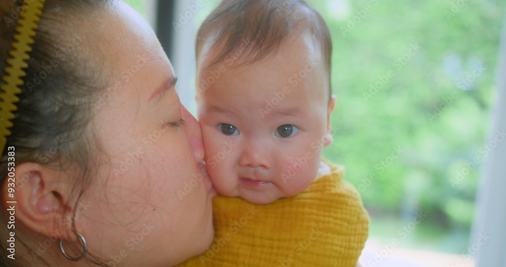 A close-up shot of a mother kissing her baby with a blurred green background, capturing a tender and loving. Tender Moment Between Mother and Baby in Bright Natural Light A close-up shot of a mother kissing her baby with a blurred green background, capturing a tender and loving. Tender Moment Between Mother and Baby in Bright Natural Light