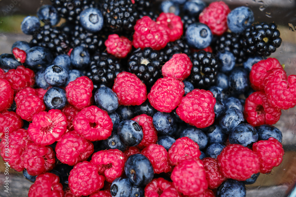 A glass plate full of summer berries on a wooden bench in the park. Fresh raspberries, blueberries and blueberries. A mix of healthy fruits. A glass plate full of summer berries on a wooden bench in the park. Fresh raspberries, blueberries and blueberries. A mix of healthy fruits.