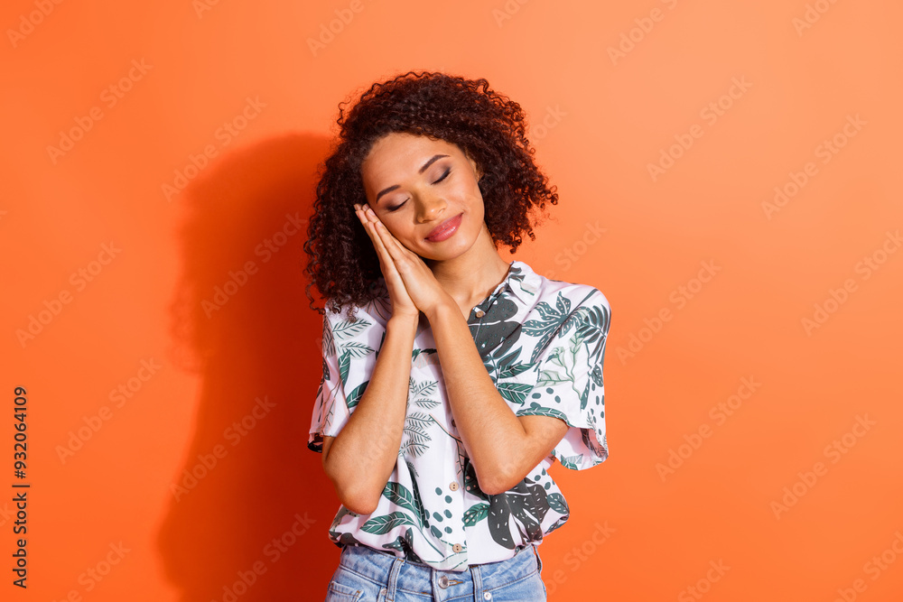 Photo portrait of funky american young positive girl with curly hair in summer shirt folded palms sleeping isolated on orange color background Photo portrait of funky american young positive girl with curly hair in summer shirt folded palms sleeping isolated on orange color background