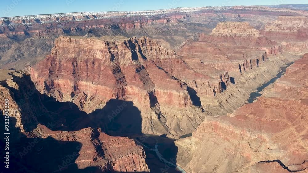 A breathtaking aerial view of the Grand Canyon and the Colorado River, as seen from a helicopter. The intricate details of the canyon walls are visible under the bright sun. A breathtaking aerial view of the Grand Canyon and the Colorado River, as seen from a helicopter. The intricate details of the canyon walls are visible under the bright sun.