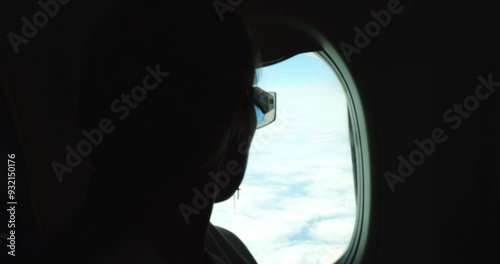 Wallpaper Mural Woman silhouette looking through window at fluffy clouds in flying airplane salon on vacation. Tranquil female passenger enjoys cloudscape travelling by plane Torontodigital.ca