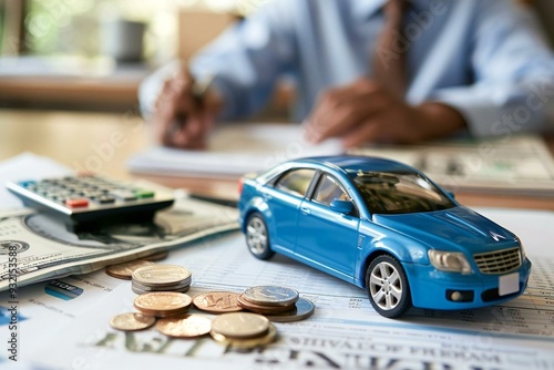 Businessman Calculating Loan with a Blue Toy Car in the foreground