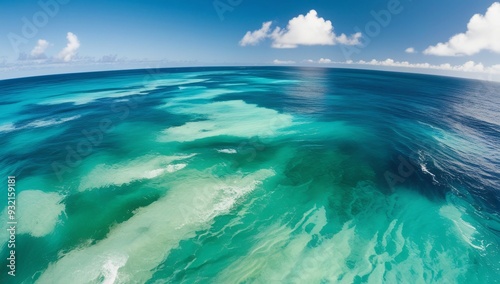 Seascape with blue sky, white clouds, and crashing waves on a sandy beach under the summer sun