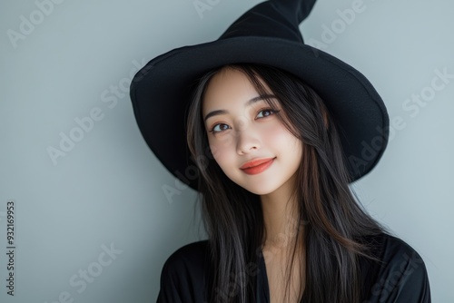 Dressed in a witch’s outfit with a pointy hat, a young woman’s confident smile embodies the mysterious and enchanting vibe perfect for Halloween celebrations.
