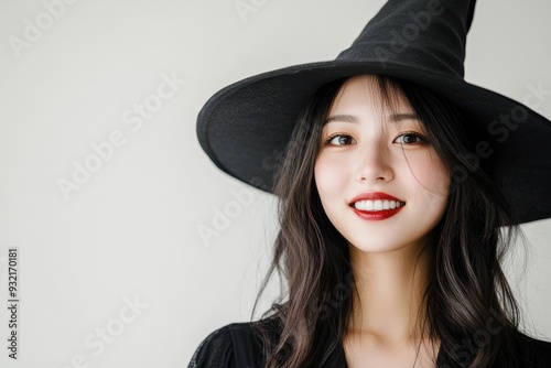 Dressed in a witch’s outfit with a pointy hat, a young woman’s confident smile embodies the mysterious and enchanting vibe perfect for Halloween celebrations.