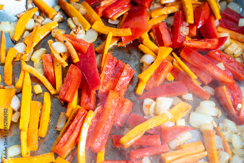 Carrots, paprika, onions and ginger cut into strips are fried in a pan. Background of their chopped vegetables.