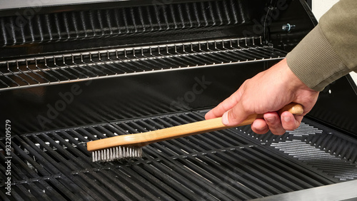 Closeup of a person cleaning a barbeque grill.