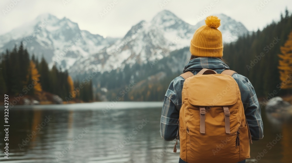Person standing by a lake with mountains in the background on a cloudy day Person standing by a lake with mountains in the background on a cloudy day