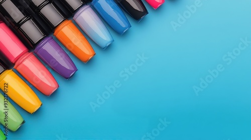 Vibrant nail polish bottles arranged on a blue surface with green leaves nearby