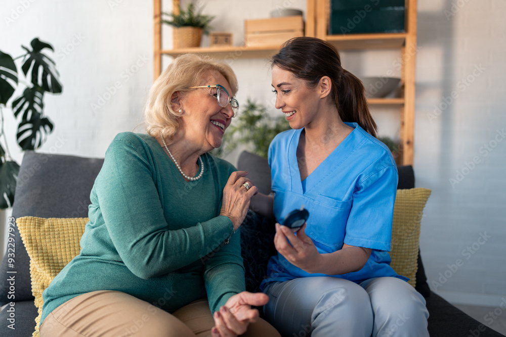 Obraz premium A diligent nurse in blue scrubs assists a gleeful elderly woman with a glucometer, ensuring her well-being in the comfort of her living room.