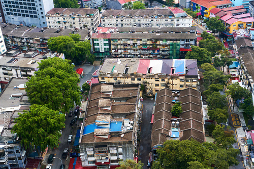 Photography An aerial view of the colored roofs of old houses that are closely stacked in a poor neighborhood in the center of the Asian city of Kuala Lumpur