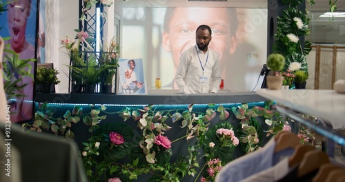 African american man checking past customers transactions in thrift shop at checkout counter and taking clothes delivery orders. Cashier in empty second hand store crosschecking data photo