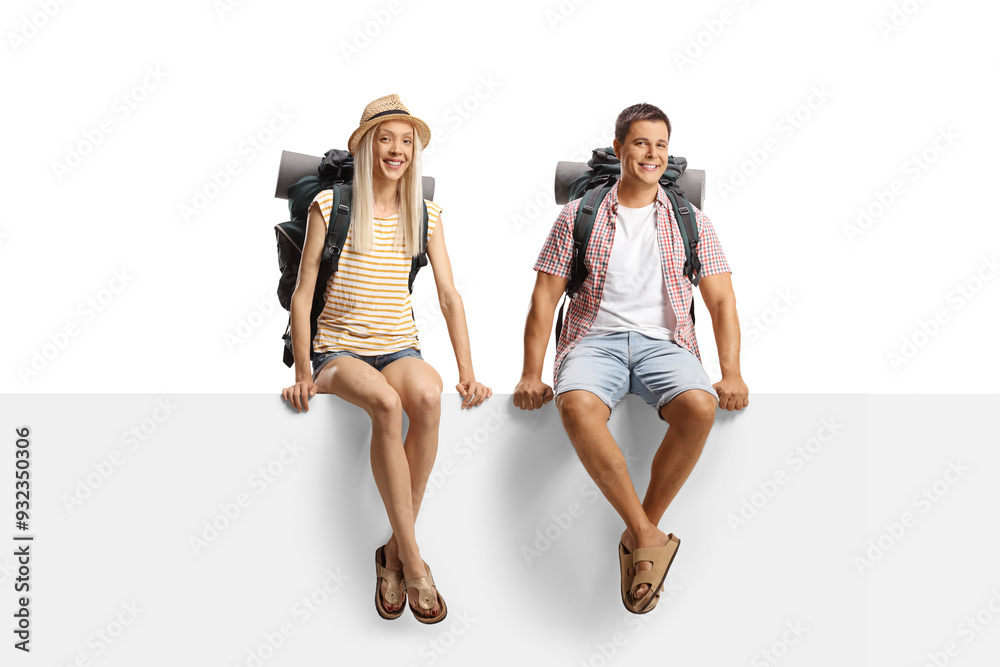 Obraz premium Male and female backpackers sitting on a blank panel and smiling