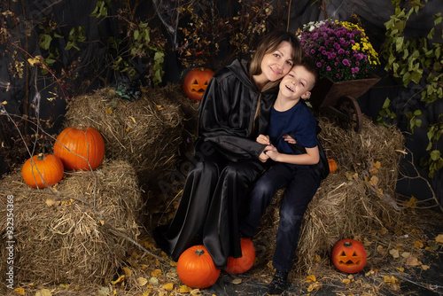 Happy mother and son playing during Halloween. cheerful family in carnival costumes in a room painted with pumpkins for the holiday of Halloween. Cheerful children playing with pumpkins and sweets photo