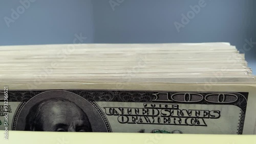 Bundle of 100 dollar bills is recalculated on counter. Phrase The unted states of america is in the center frame. Concept tax and mortgage