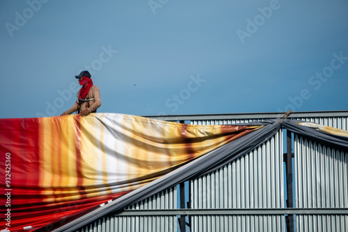 worker installing a large advertising banner on a billboard structure photo