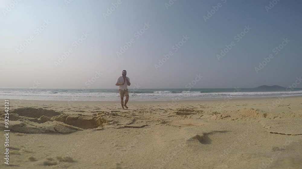 Running and walking on the beach during a sunny morning. Aerial view with camera following the person. Running and walking on the beach during a sunny morning. Aerial view with camera following the person.